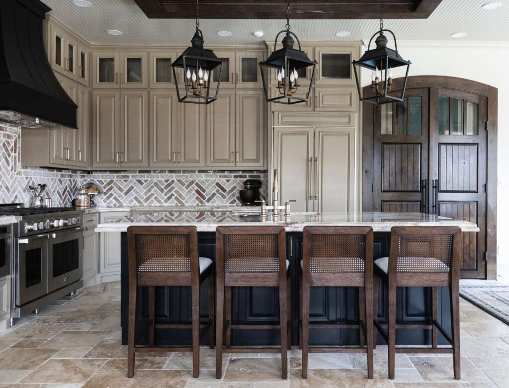 photograph of kitchen showing back of chairs at kitchen island and brick backsplash
