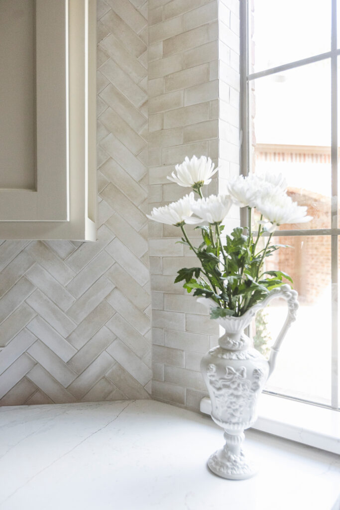 Home Remodeling Services Forest Hills, TX - image of smooth white countertop with white flowers in vase near glass window with natural light shining through​
